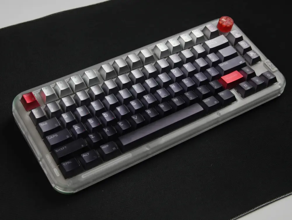 Angled keyboard with a pale upper row, charcoal dot-matrix keys, and red accents.