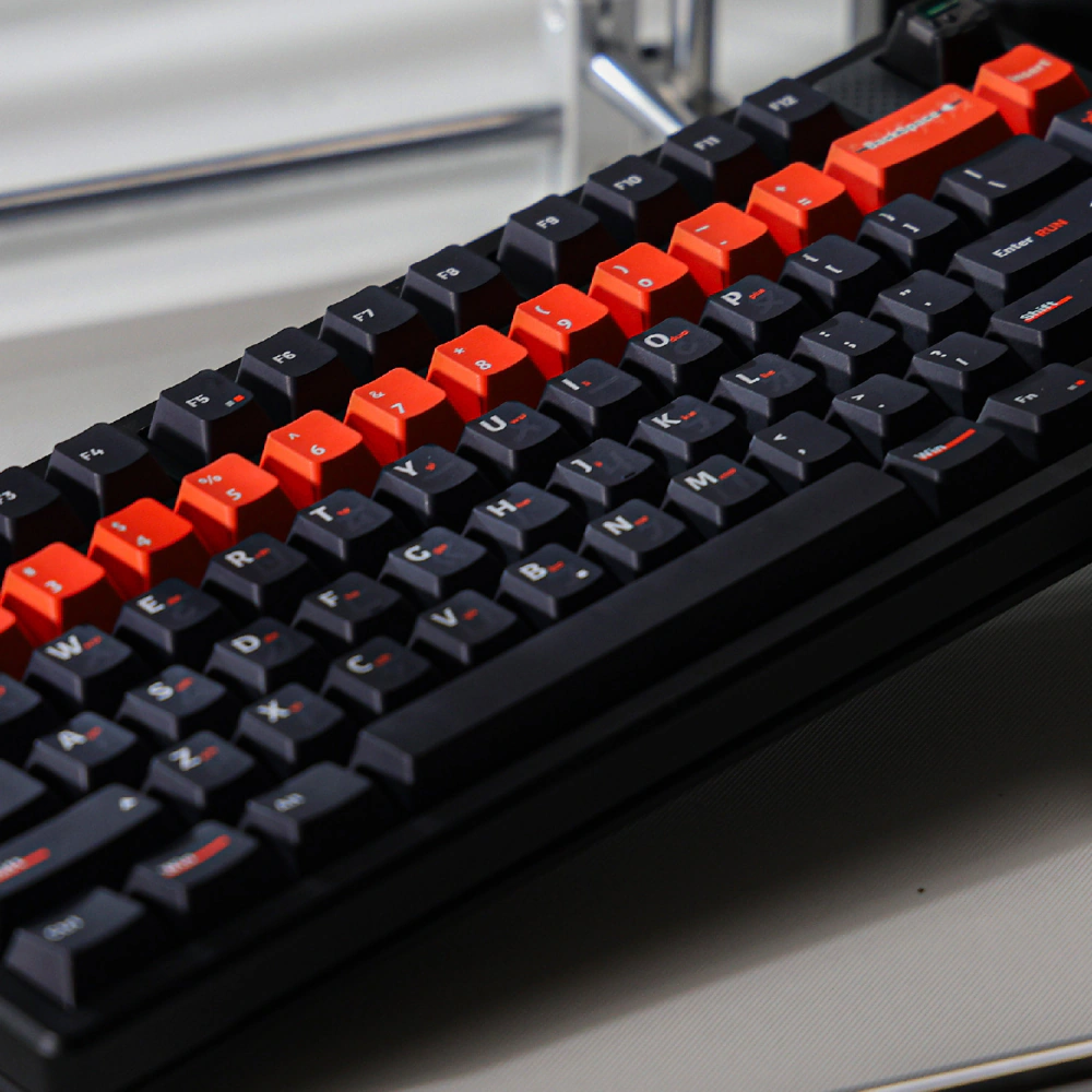 Dark keycaps and orange number keys shown diagonally on a black keyboard.