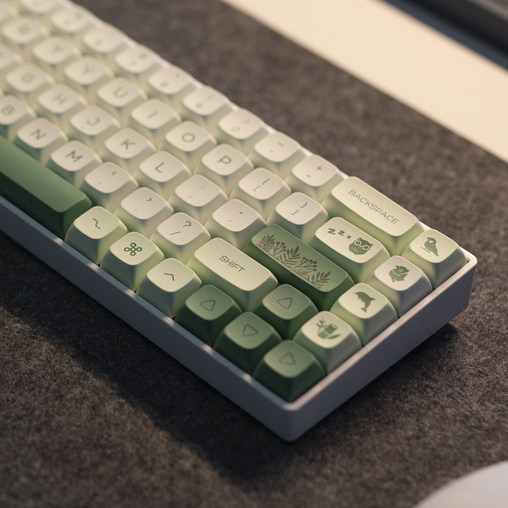 Green Botanical Keycaps Corner Detail Close-up of green and white keycaps with animal, leaf, and arrow key details.
