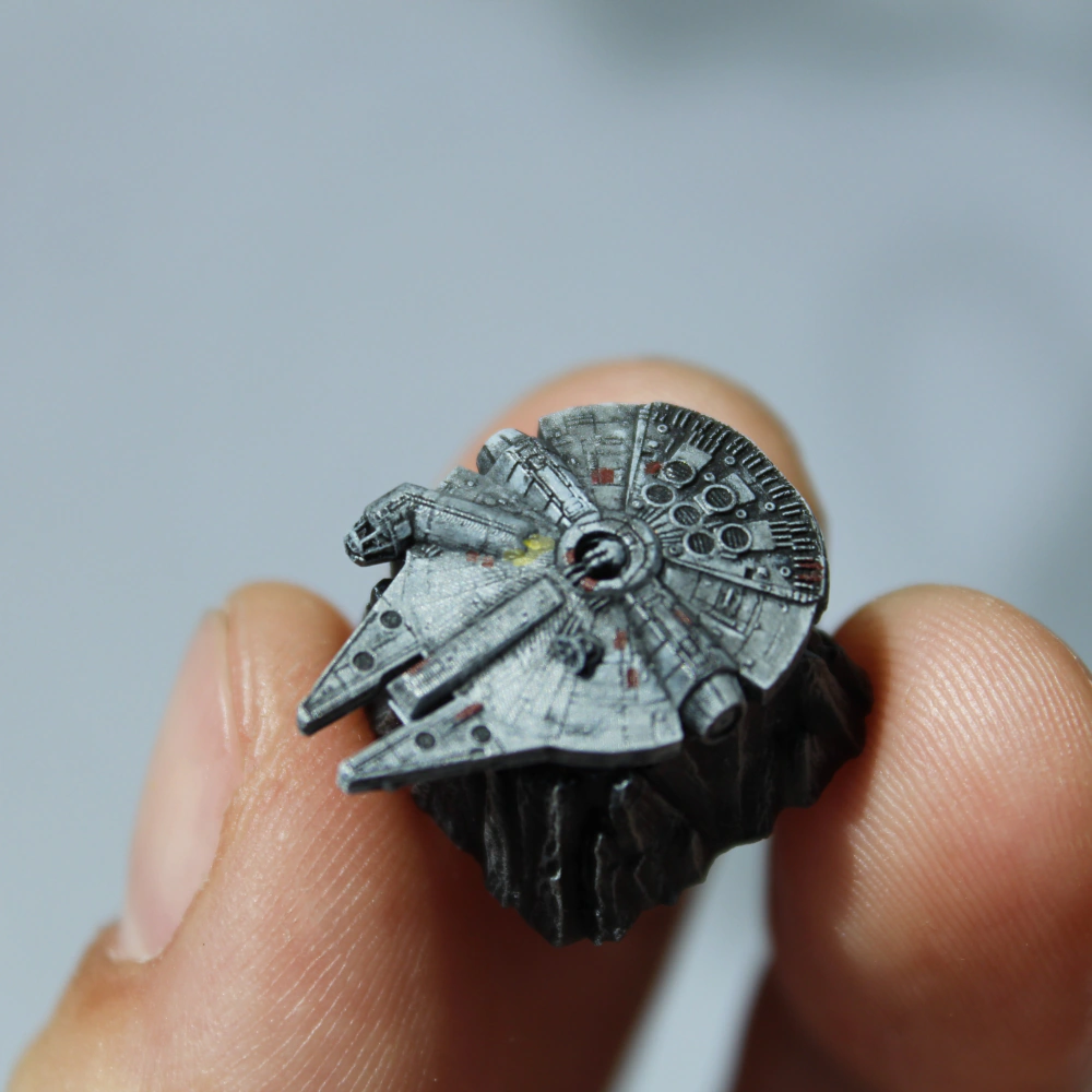 Handheld Millennium Falcon Keycap Detail A person holds the gray Millennium Falcon keycap between fingers against a pale background.
