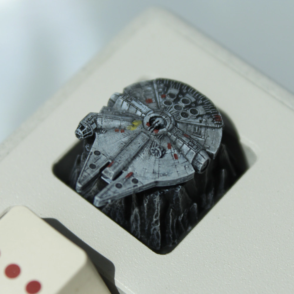 Millennium Falcon Keycap on Keyboard Gray Millennium Falcon keycap mounted among light-colored keys with red markings.