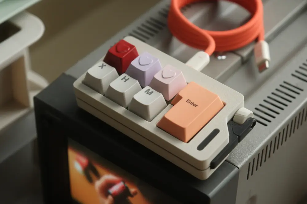 Compact keyboard with colored heart keycaps on a desktop surface.