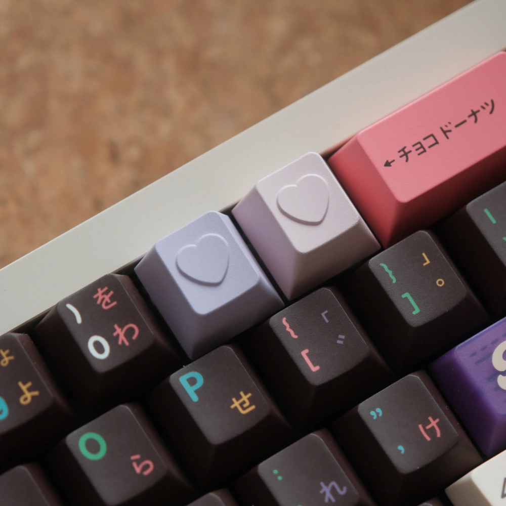 Two light heart-shaped keycaps installed on a dark keyboard.