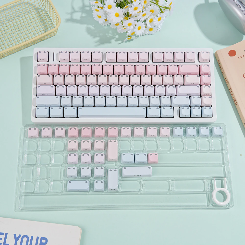 Pink-blue gradient keycaps arranged in a transparent storage tray