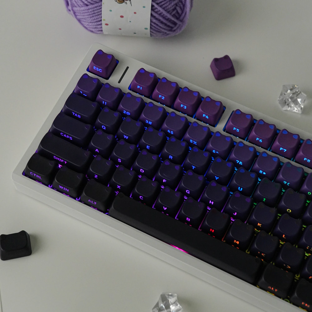 Backlit purple-black keycaps with shine-through cat-ear shapes and side-printed legends