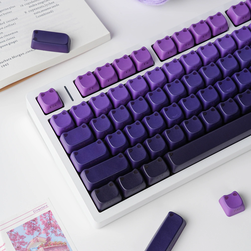 Purple-black cat-ear keycaps on a white keyboard with loose caps and clear decorative pieces