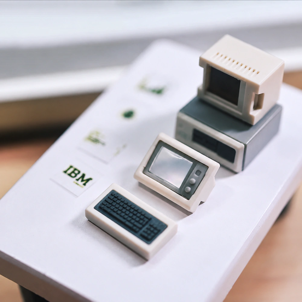 Beige mini computer body, detached screen and small keyboard pieces, and several picture cards laid out on a white surface.