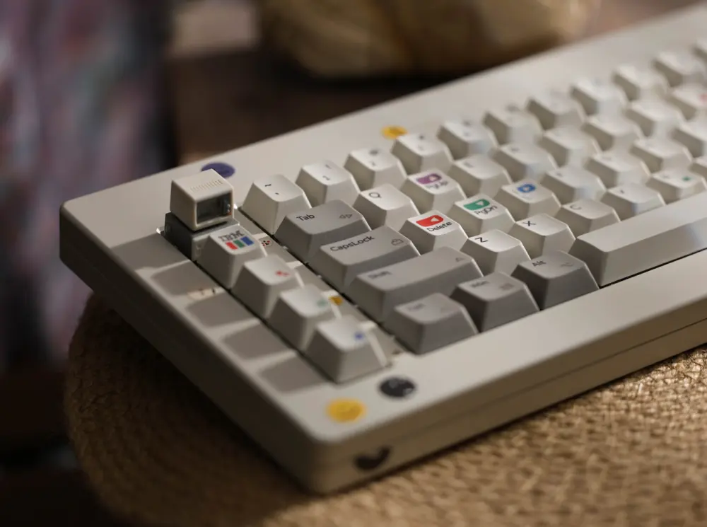 A small beige monitor-shaped keycap sits above an IBM color-bar key on a gray keyboard.