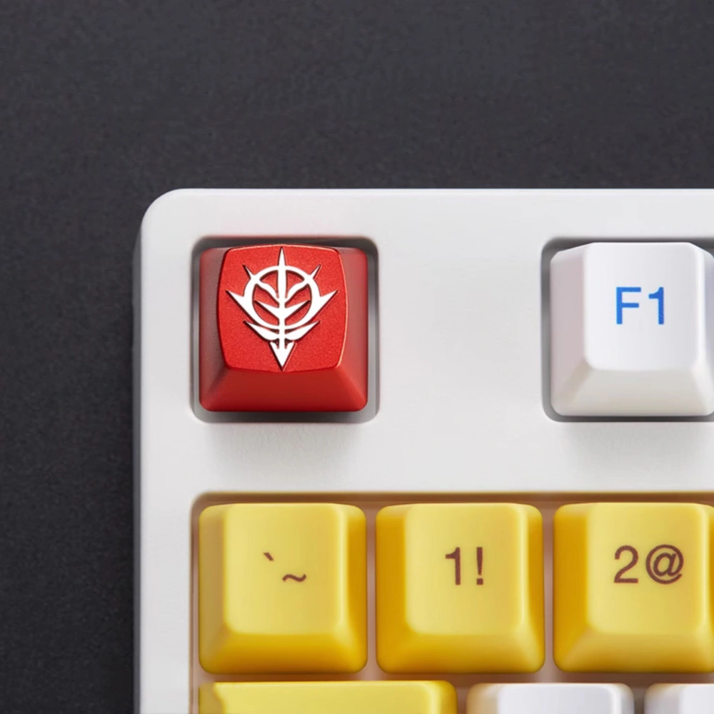 Red Zeon emblem keycap installed on a white mechanical keyboard beside yellow keys.