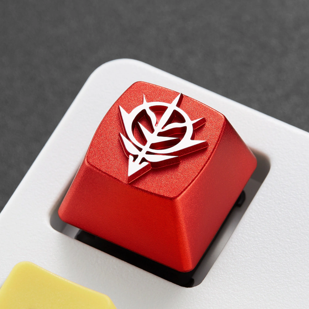 Red Zeon emblem keycap shown from the side on a dark textured surface.