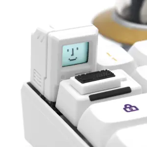 White computer-shaped keycap with a pixel face on its screen, installed beside its mini keyboard piece.