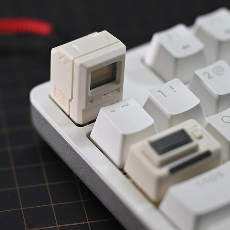 Cream computer-shaped cap with a smiling screen on white keys, with the mini keyboard piece in front.