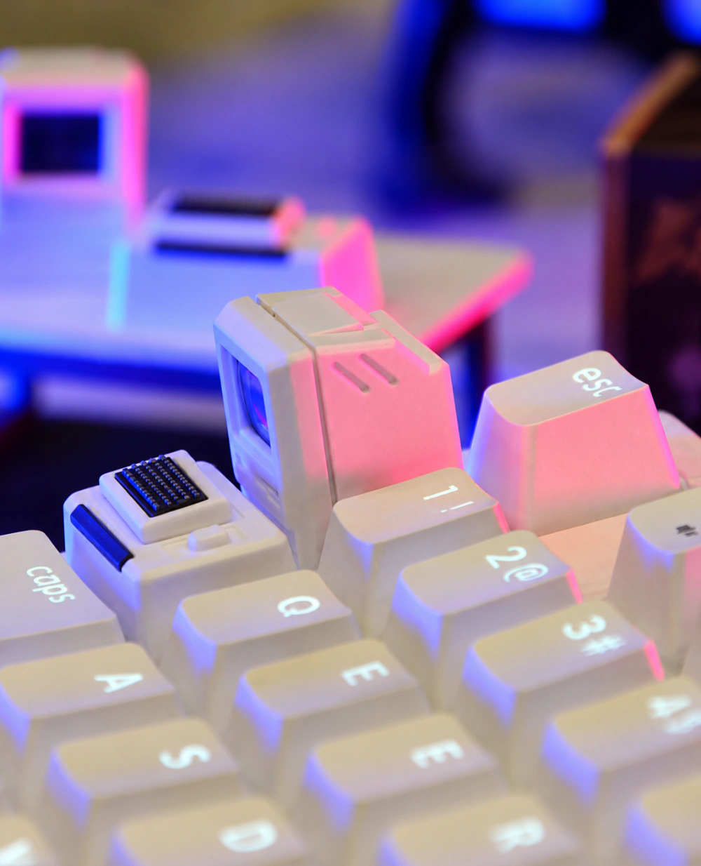 Side view of a white computer-shaped keycap with a pink-lit case, beside Esc and number-row keys.