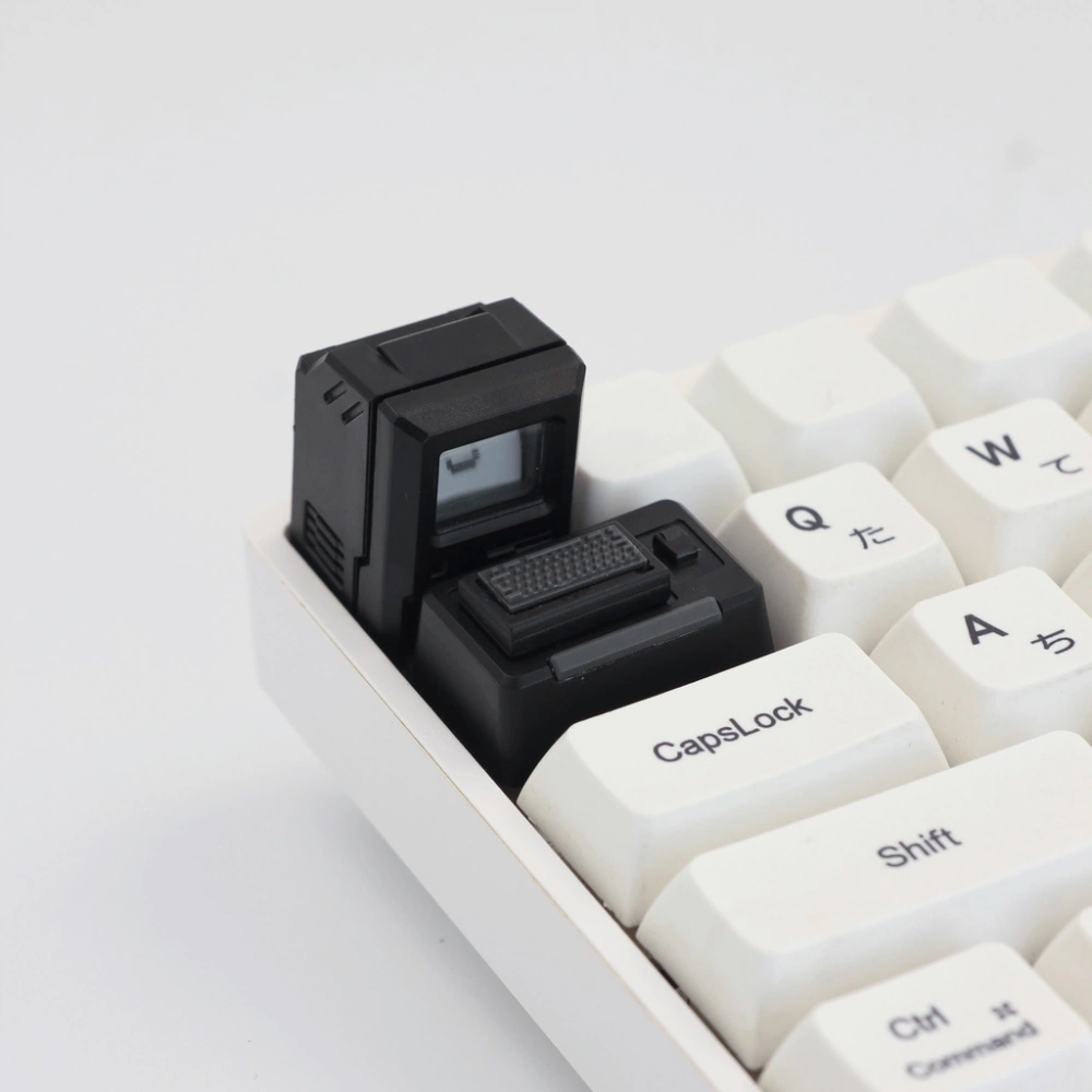 Black Macintosh-style cap and mini keyboard on a white keyboard, with nearby Caps Lock and Shift keys visible.