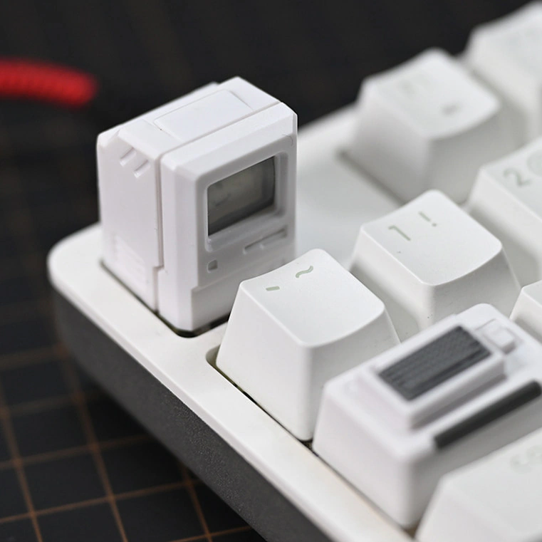 White Macintosh-style cap with a reflective screen on white keys, with the mini keyboard piece in the foreground.