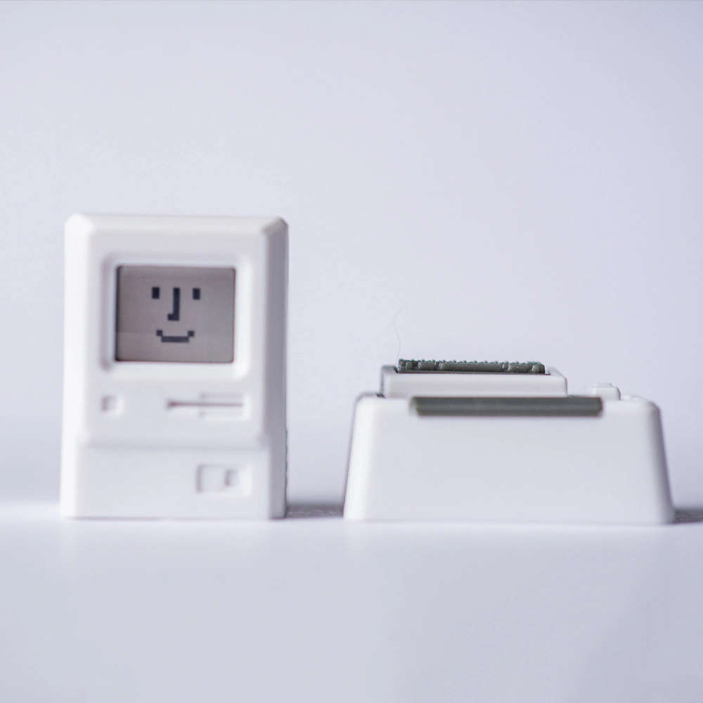Front view of a white miniature computer cap and its small keyboard piece on a white background.