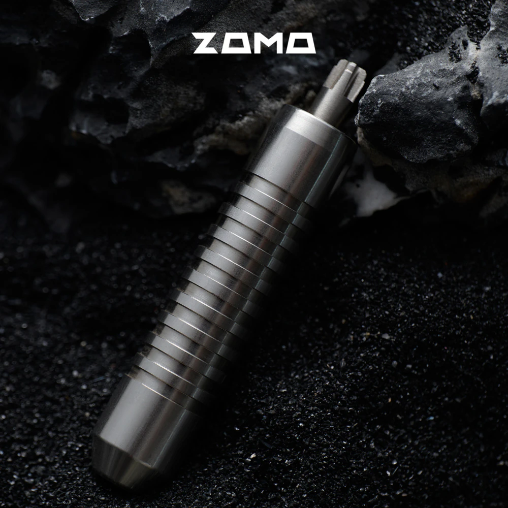 The grooved adjuster points upward against a dark background with rocks.
